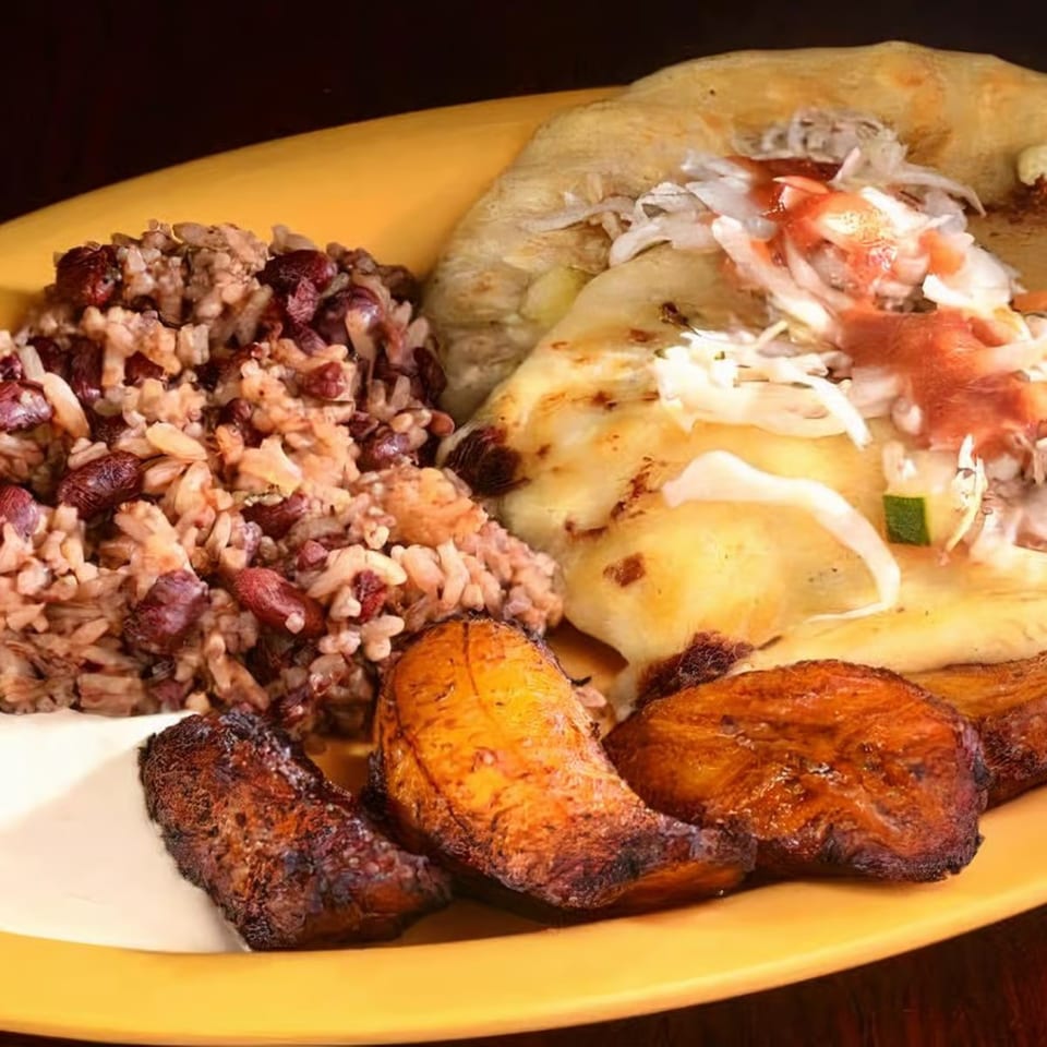 A yellow plate with rice and beans, pupusas topped with curtido and salsa, and fried plantains.
